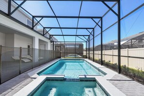 A covered swimming pool with a clear view of the sky and a fence on one side. - Amazing 10BR Jurassic World in Windsor Island (Davenport)