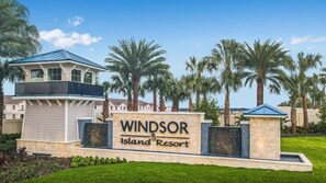 A resort sign with the name "Windsor Island Resort" and a building with a blue roof and balcony. - Amazing 10BR Jurassic World in Windsor Island (Davenport)