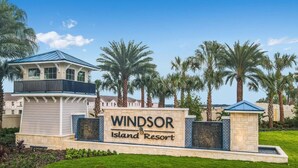 Une enseigne indiquant le «Windsor Island Resort », avec en arrière-plan des palmiers et un bâtiment doté d’un toit bleu.