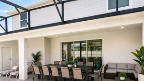 Une terrasse extérieure couverte, aménagée avec une table à manger, des chaises, un canapé et une piscine.