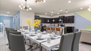 Une cuisine moderne avec des meubles de couleur sombre, un îlot central et des luminaires suspendus.