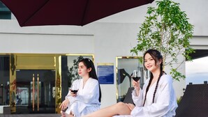 Two individuals seated on wicker lounge chairs outdoors, holding wine glasses. - Landmark Vientiane Life Center (Vientiane)