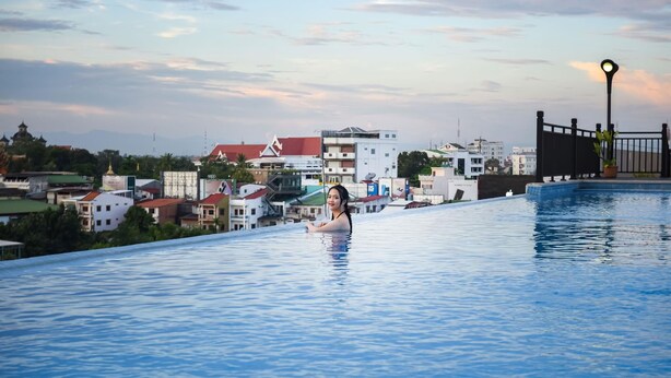 A swimming pool with a person in the water, surrounded by buildings and a clear sky. - Landmark Vientiane Life Center (Vientiane)