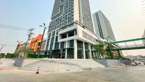 A multi-story building with a prominent entrance, steps leading up to it, and a pedestrian overpass above. - Landmark Vientiane Life Center (Vientiane)
