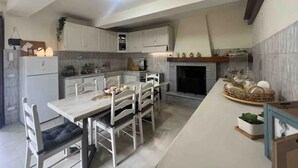 A modern kitchen with white cabinetry, a dining table with chairs, a built-in oven, and a fireplace.