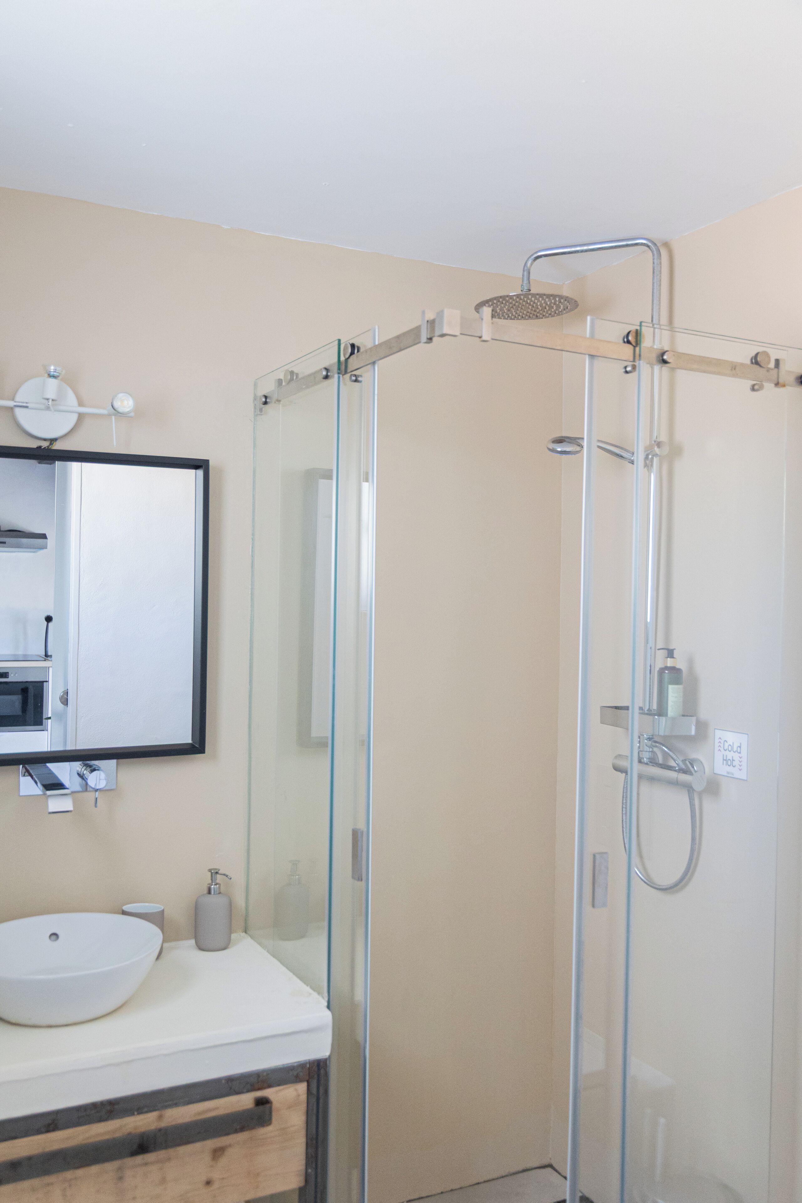 Un baño moderno con ducha de vidrio, un lavabo blanco y un espejo sobre el lavabo.