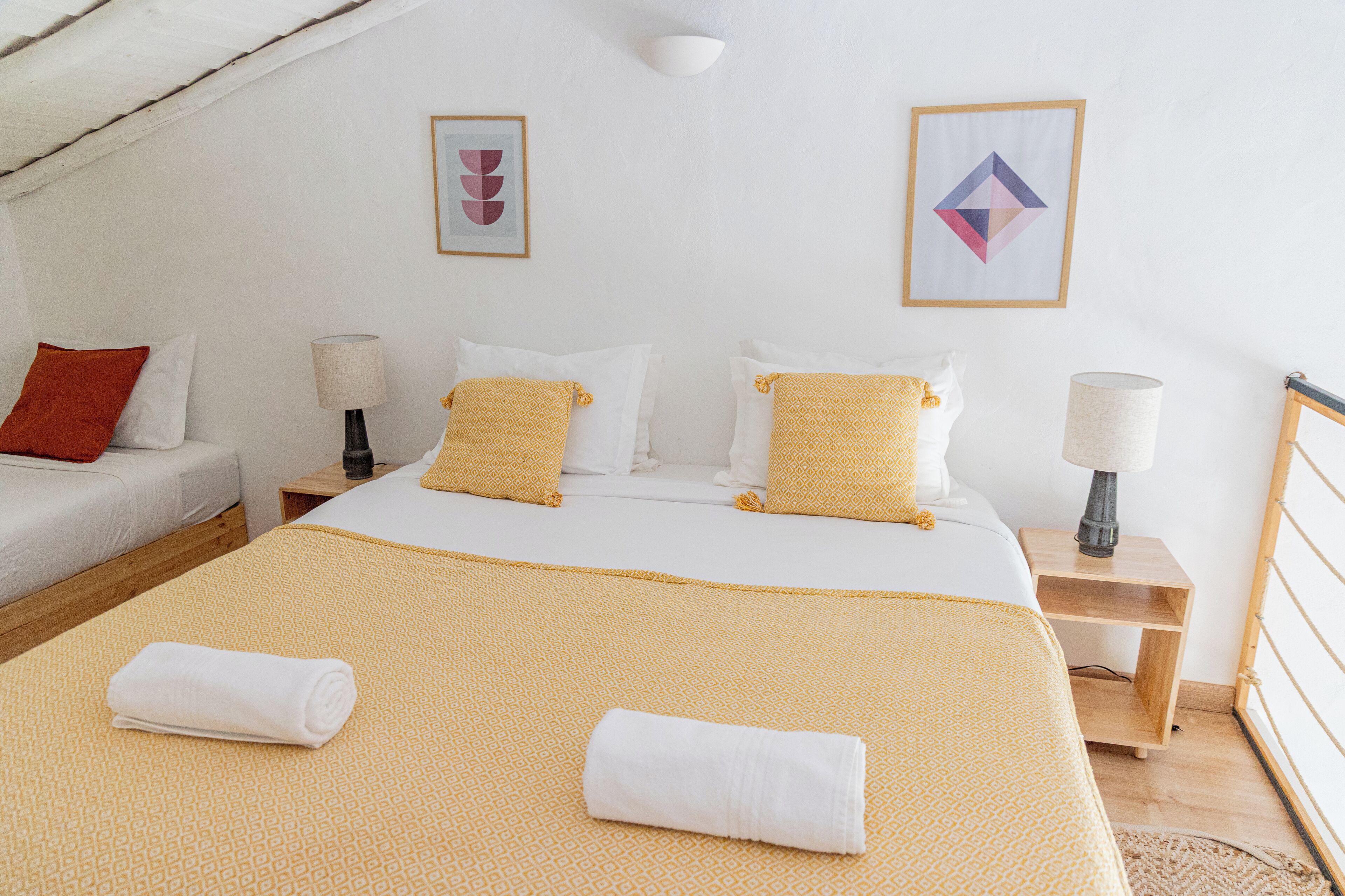 A hotel room with a large bed, two bedside tables, a nightstand, and a small desk.