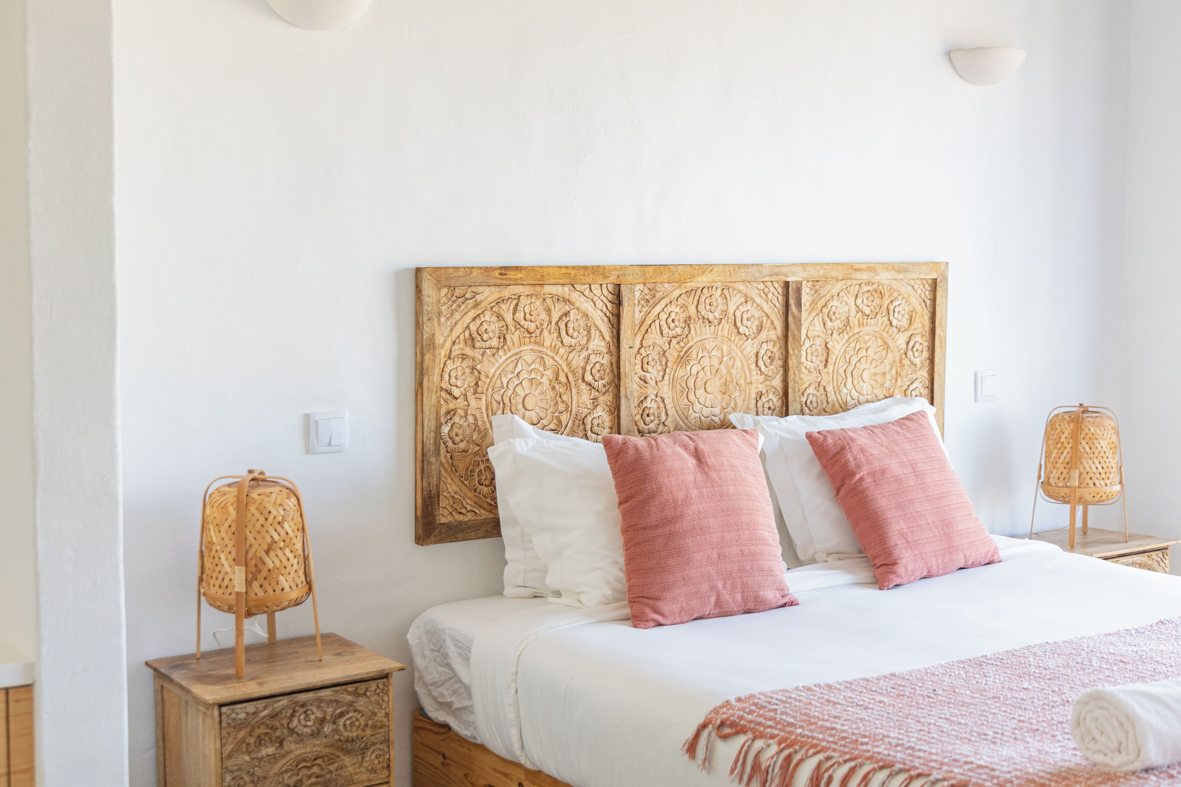 A bedroom with a wooden headboard, white bedding, and two bedside lamps.