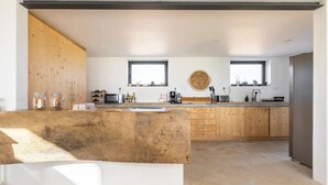 Een moderne keuken met houten kasten, een centraal eiland en een groot raam dat voor natuurlijk licht zorgt.