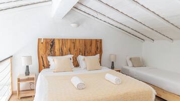 A bedroom with a wooden headboard, two beds, and a small bedside table with a lamp.