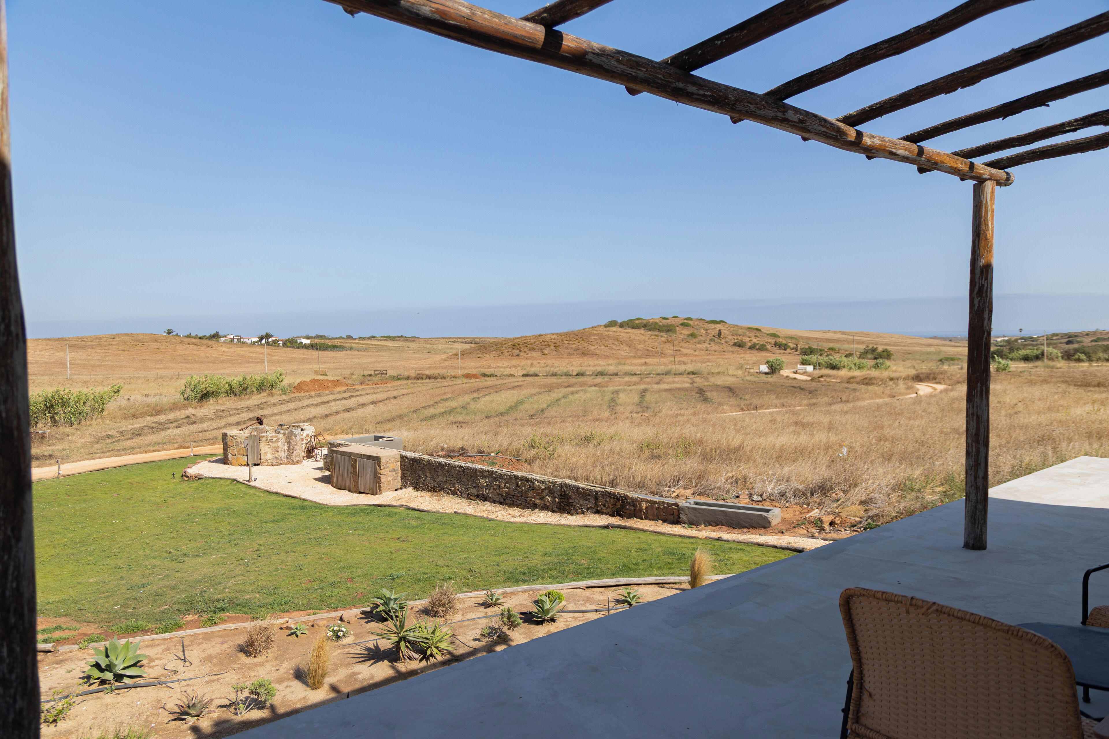 A patio area with a view of a hilly landscape and a body of water.