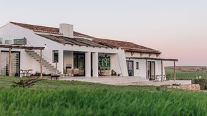 Een modern huis met een witte gevel, een pannendak en een overdekte patio met tuinmeubilair.