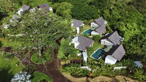 Vista aérea de un resort con varias villas, una piscina y abundante vegetación.