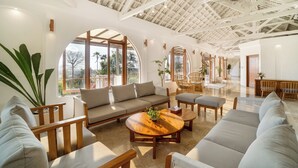 Un salón espacioso con techos altos, ventanas amplias y diversas opciones de asiento, como sofás y sillones.