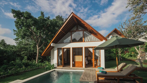 Una casa moderna con un amplio ventanal de vidrio, una terraza de madera y una piscina.