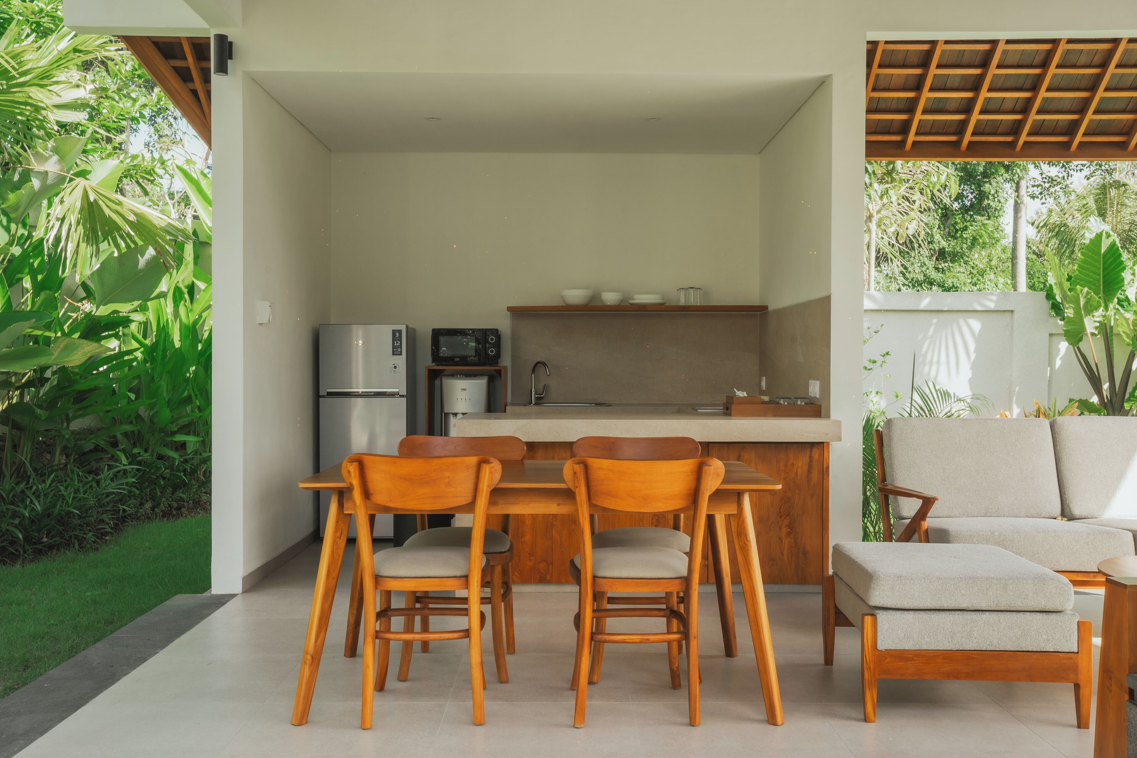 Une cuisine moderne avec des chaises en bois et un canapé, le tout entouré de verdure.