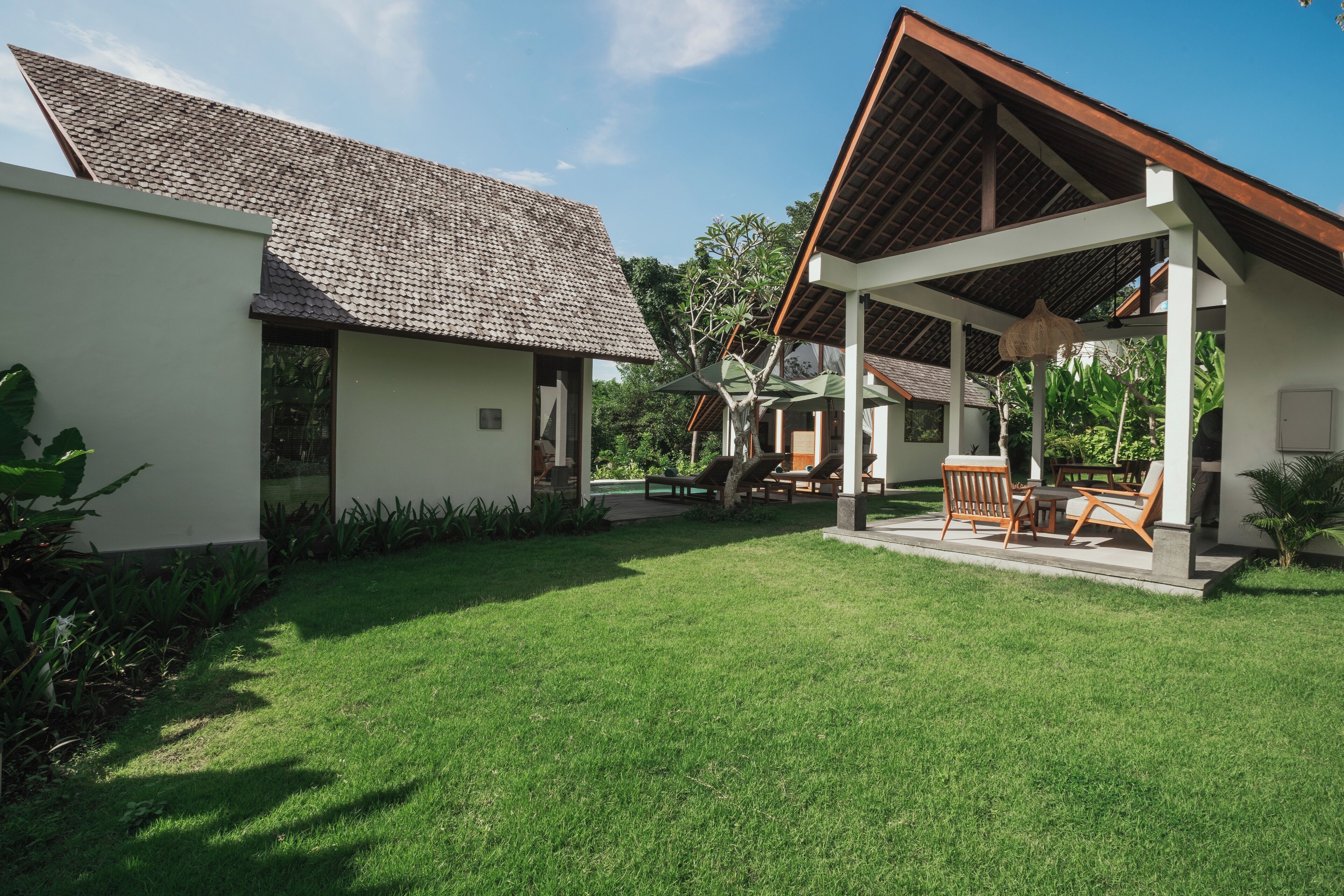 A modern building with a tiled roof and a covered patio area with outdoor furniture.