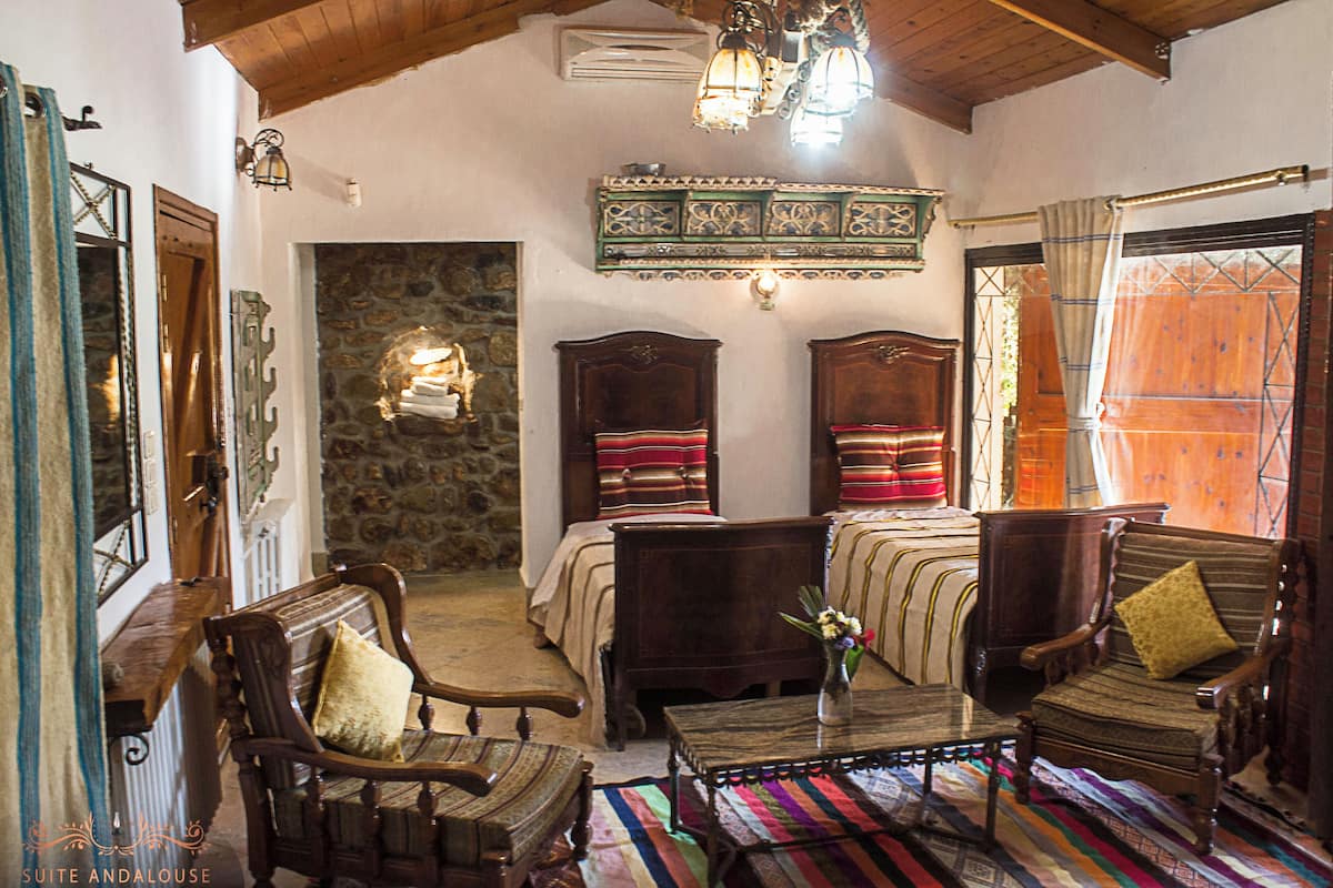 Una habitación tradicional con chimenea de piedra, muebles de madera y un colorido tapete a rayas.