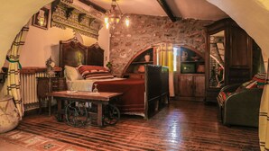 A cozy room with a wooden bed, a table with a wine glass, and a stone wall. - Dar Zaghouan (Zaghouan)