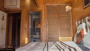 A wooden cabin interior with a bed, a bathroom, and a kitchen area. - Dar Zaghouan (Zaghouan)