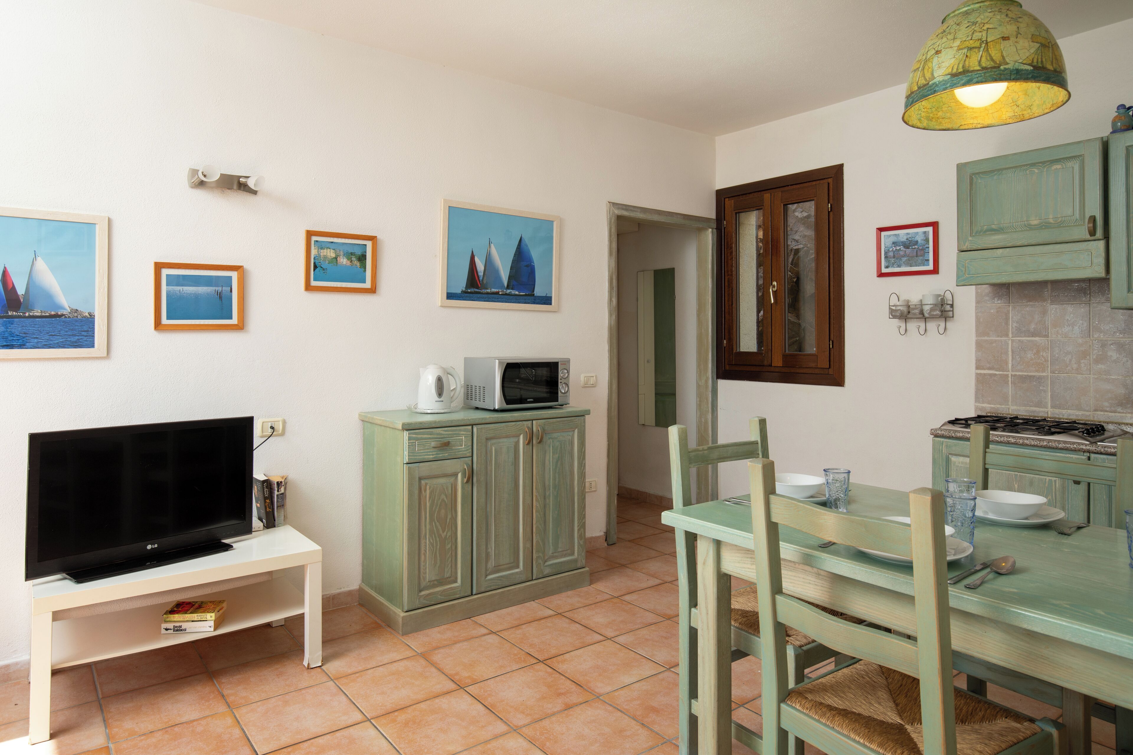 A compact kitchen with a TV, microwave, and dining table set for four.