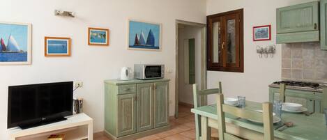 A compact kitchen with a TV, microwave, and dining table set for four.