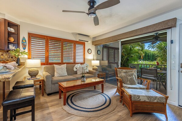 A spacious living room with a sofa, chairs, a coffee table, and a dining area with a table and chairs. - Poolside peace, garden views in a modern setting (Kihei)