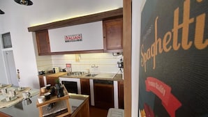 A kitchen with wooden cabinets, a whiteboard, and a sign reading 'Authentic Italian Cuisine.' - Lhe srl Beating Heart (Cesena)
