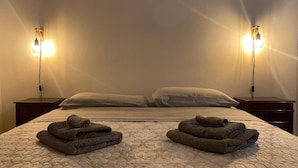 A hotel room with a large bed, two bedside lamps, and a neatly folded towel on the bed. - Lhe srl Beating Heart (Cesena)