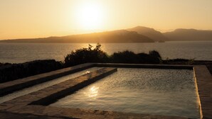 A swimming pool with a view of the sunset over the water. - Experience your personal leap into time on Therasia island (Thirasia)