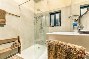 A modern bathroom with a glass-enclosed shower, a large bathtub, and a wooden shelf with towels. - Retro Designer Homelike Apartment - Close to Beach (Munxar)