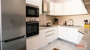 A modern kitchen with a Bosch refrigerator, a microwave, an oven, and a sink. - Seaside Magic From a Stunning Apartment (St. Paul's Bay)
