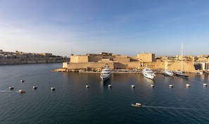 A harbor with several yachts docked, a fortified building, and a clear sky. - Eclectic Apartment With Incredible Harbour Views (Senglea)