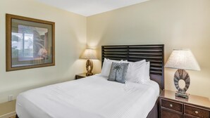 A neatly made bed with white linens, a dark headboard, and two bedside tables with lamps.