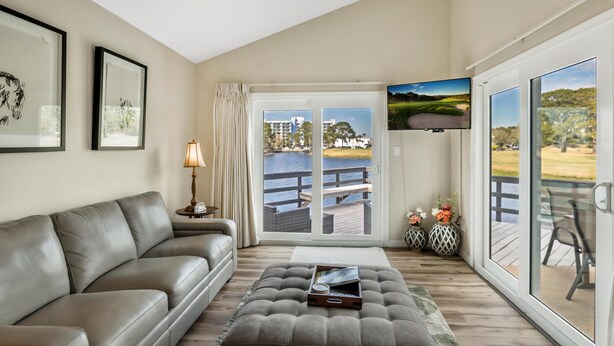 A living room with a sofa, a coffee table, a TV, and a sliding glass door leading to an outdoor deck.