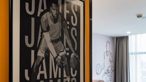 A framed poster of a basketball player on a hotel wall, a bed, and a window with curtains. - Avo Sport Résidence, Diamniadio (Diamniadio)