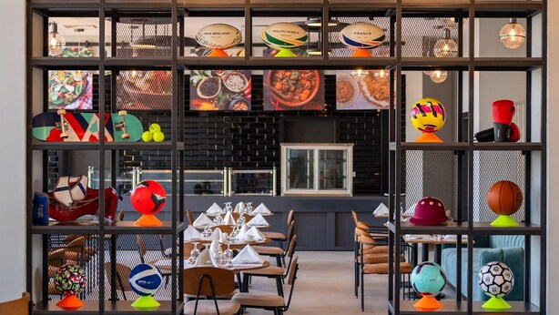 A modern restaurant interior with high ceilings, pendant lighting, and a central dining area with tables and chairs. - Avo Sport Résidence, Diamniadio (Diamniadio)