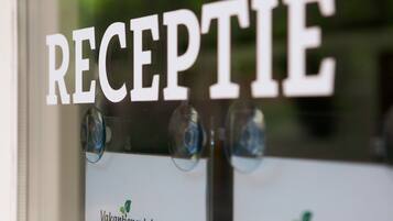 A reception area with a sign that reads "RECEPTION" and two name tags for "Vakantiepark Latour" and "Kempen Recreatie".