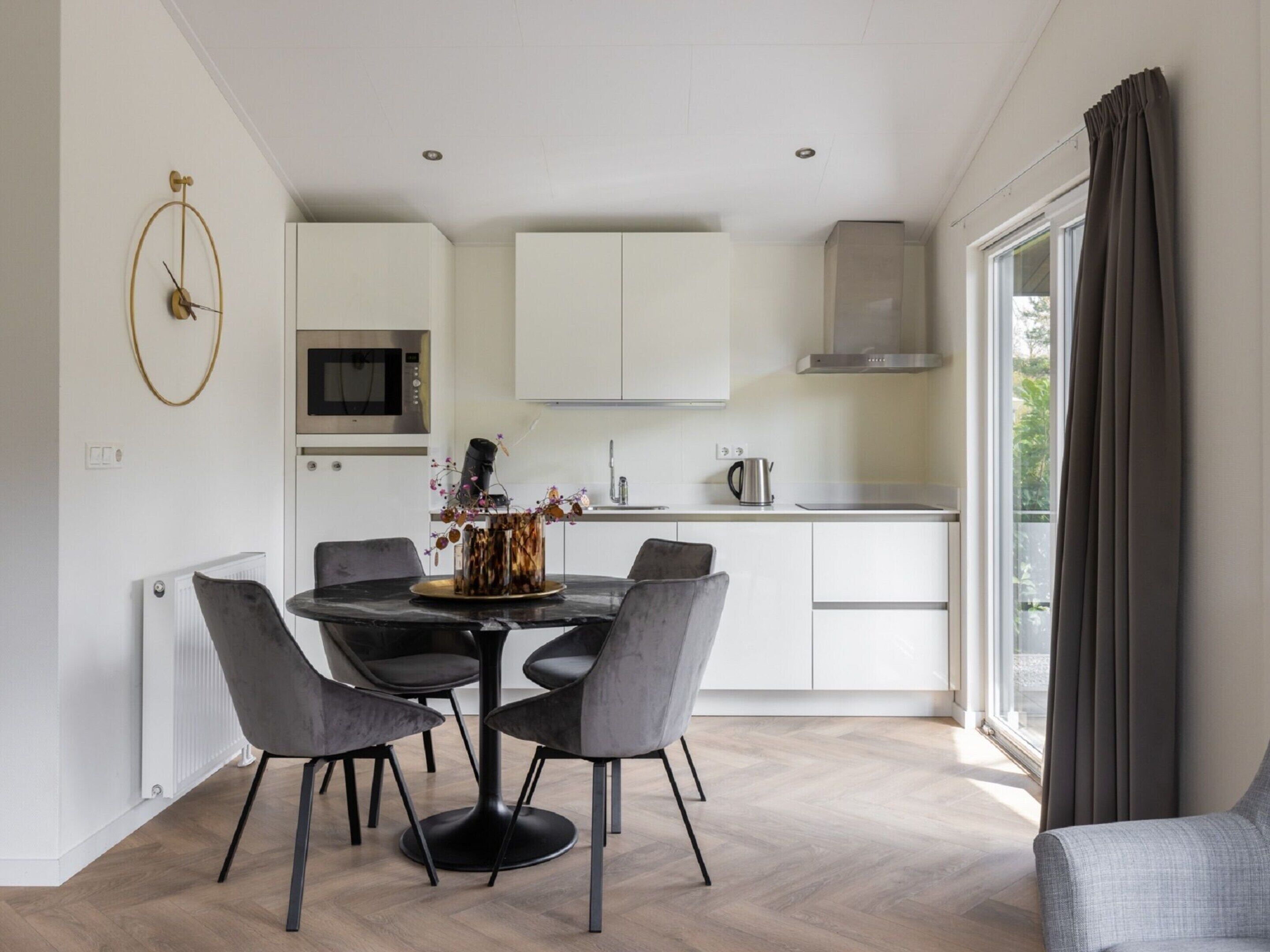 A modern kitchen with white cabinets, a central island with chairs, and a dining table.