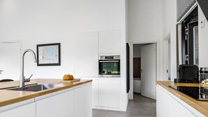 A modern kitchen with a wooden countertop, stainless steel sink, and an oven.