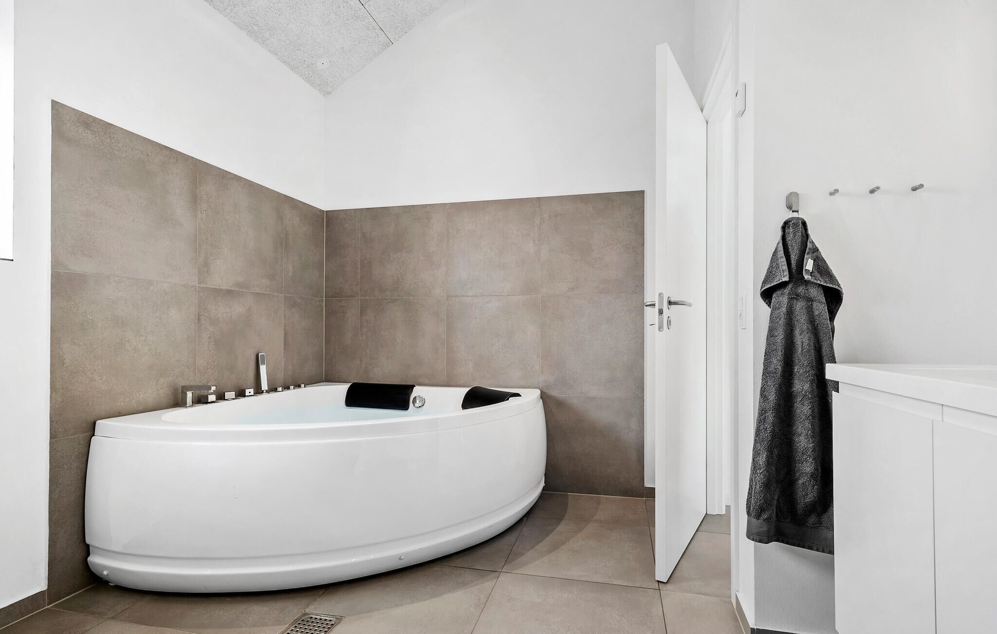 Une salle de bain moderne avec une baignoire sur pieds, un lavabo blanc et un porte-serviettes.