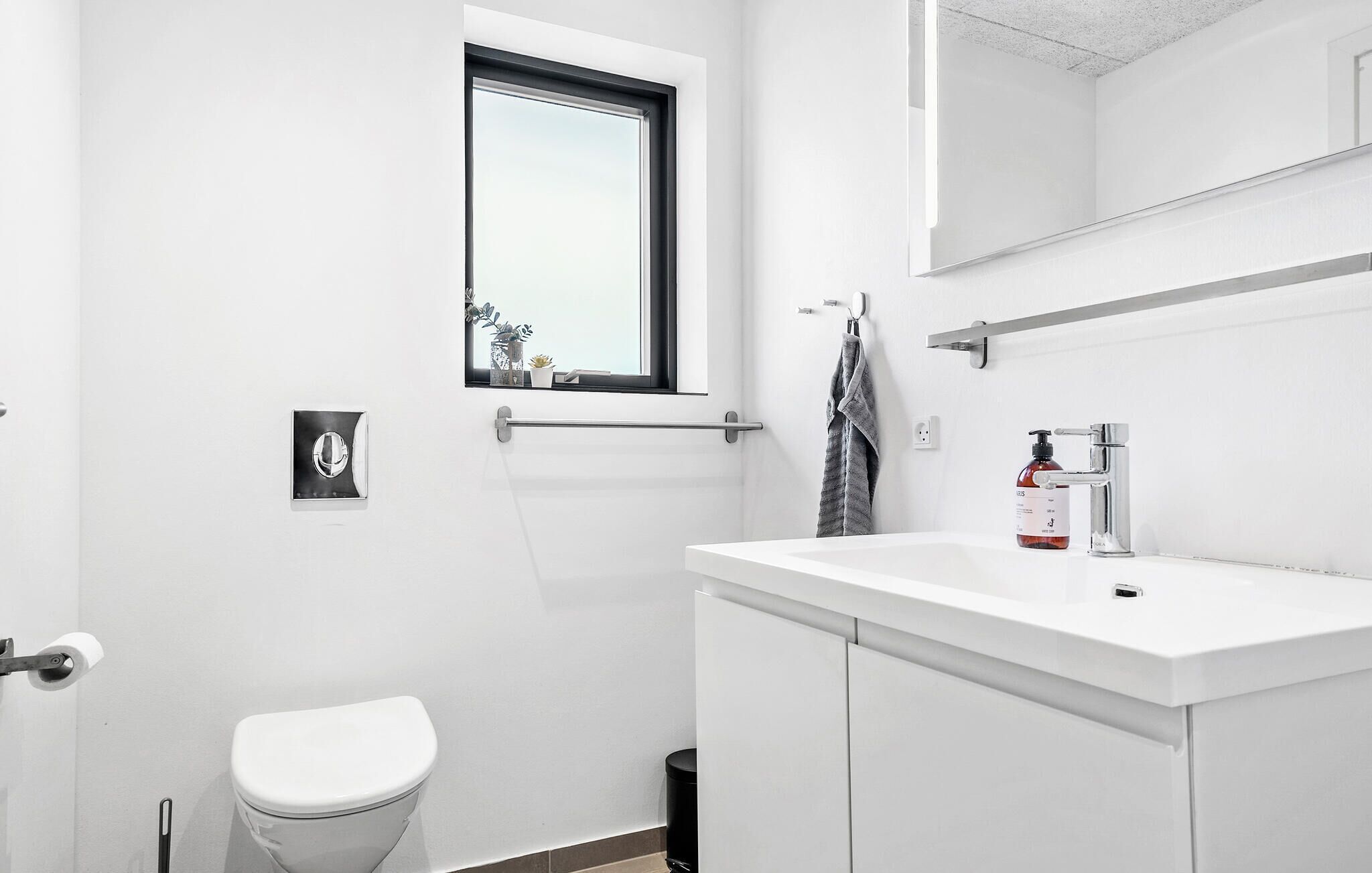 Een moderne badkamer met toilet, wastafel en raam.