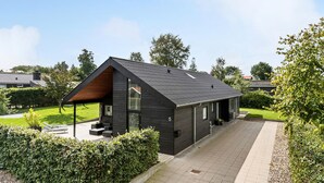 A modern two-story house with a dark exterior, a sloped roof, and a paved driveway.