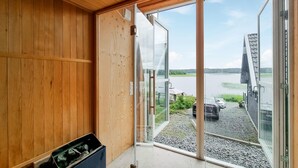 Una stanza con pareti in legno e un'ampia porta scorrevole in vetro che dà su un lago e un pontile con una barca.