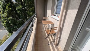 A balcony with a tiled floor, two wooden tables, and two chairs.