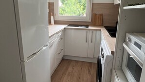 A compact kitchen with a refrigerator, oven, microwave, and sink.