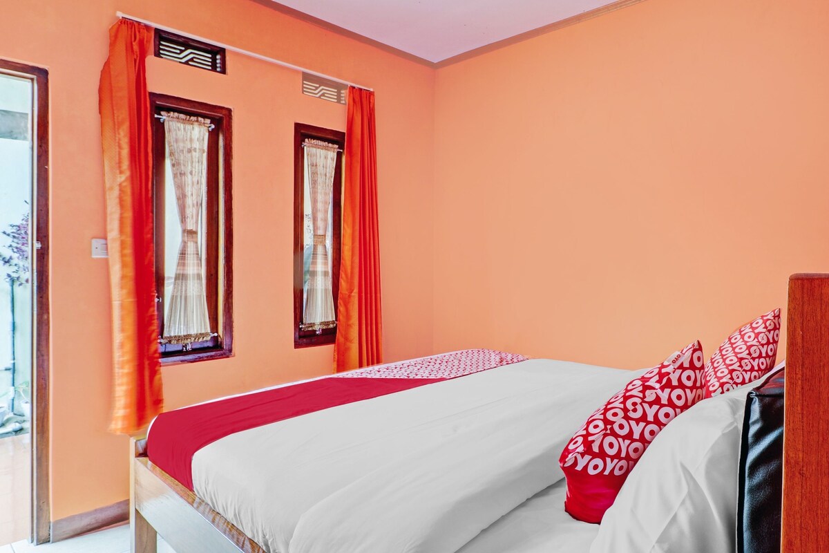 Un dormitorio con cama, dos ventanas con cortinas y vistas al exterior.