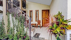 Un escalier menant à un palier agrémenté de plantes en pot et d’une porte.
