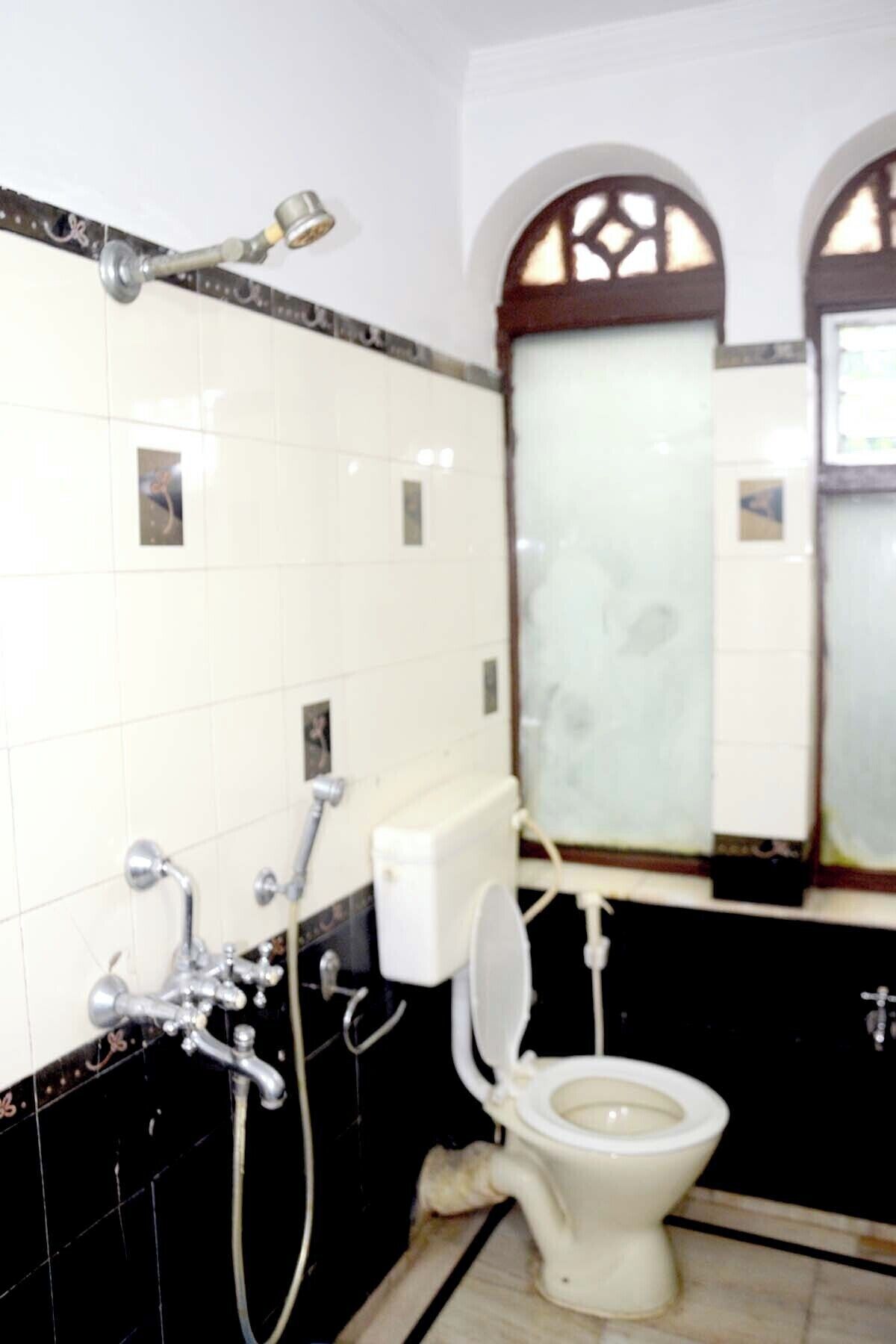 A bathroom with a toilet, a shower, and a mirror.