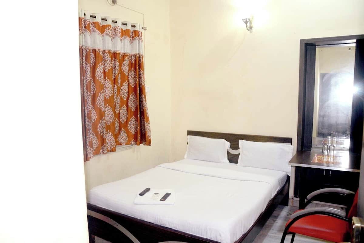A hotel room with a bed, a desk, a chair, and a window with curtains.
